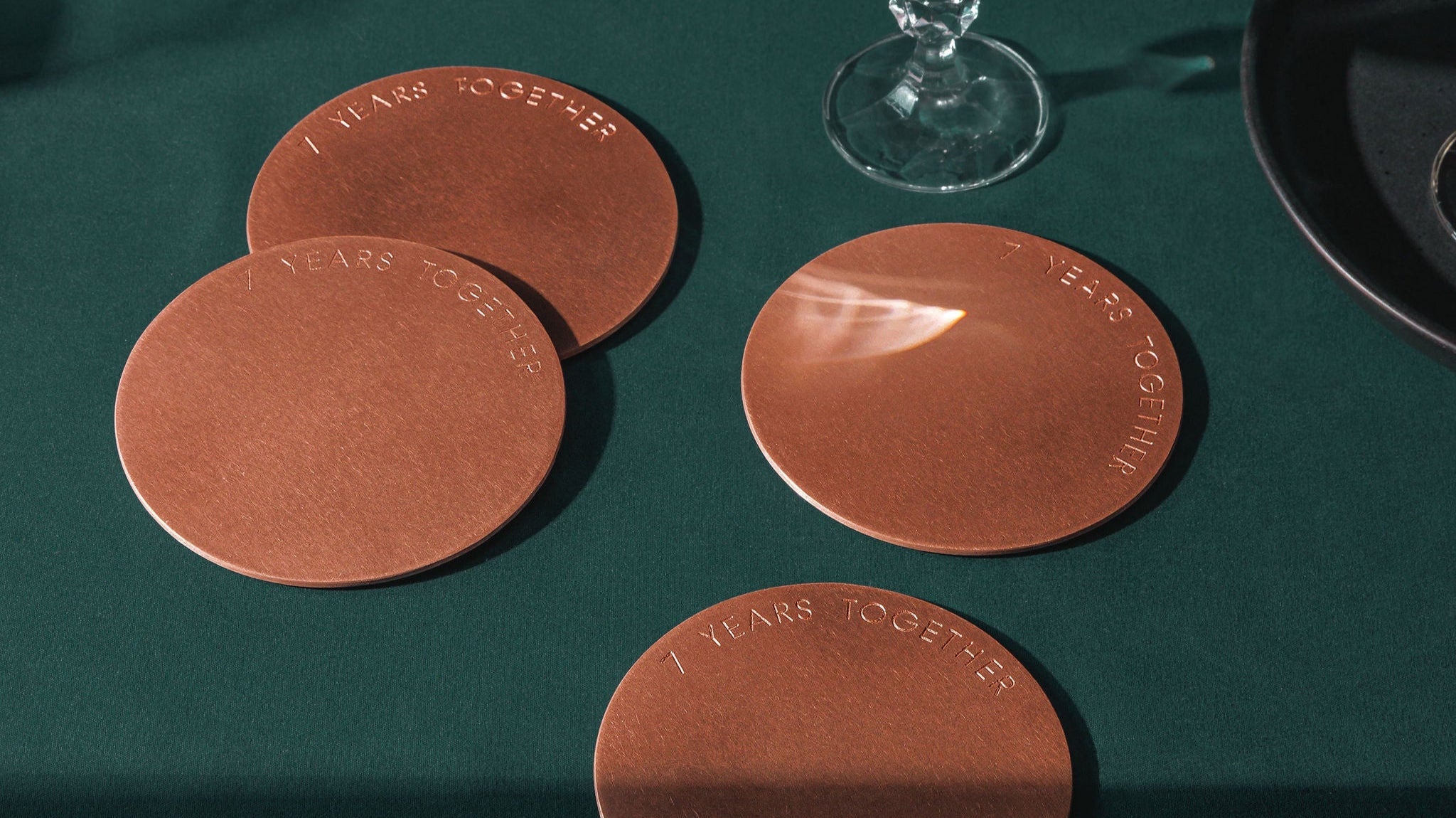 A set of 4 copper coasters engraved with the message "7 Years Together". The coasters are made by Empire Copper by Hayes Home.