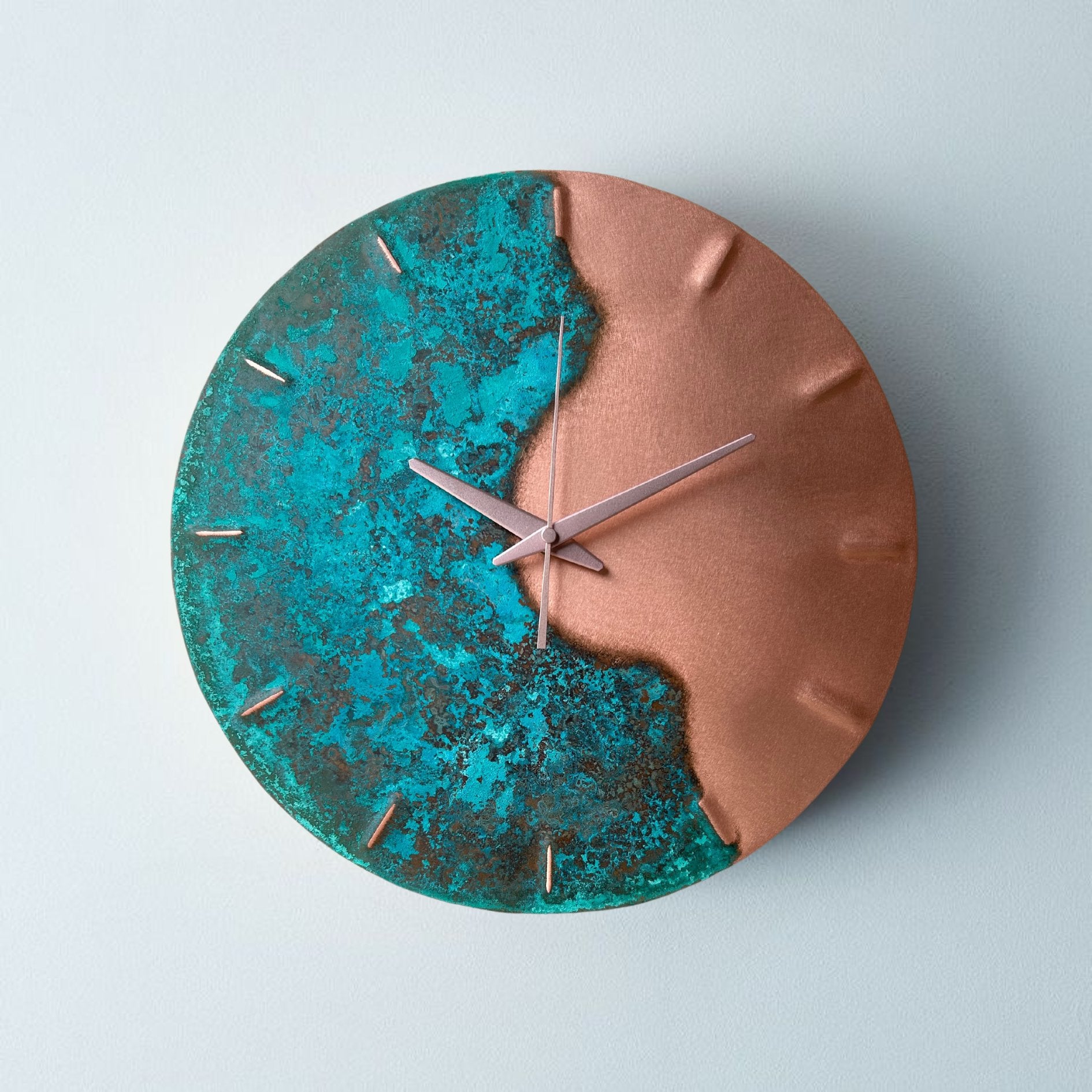 A 35cm diameter, round copper clock. The left handside has a turquoise, verdigris patina and the right hand-side is pure brushed copper. The clock hands are copper. The clock is made by Empire Copper.