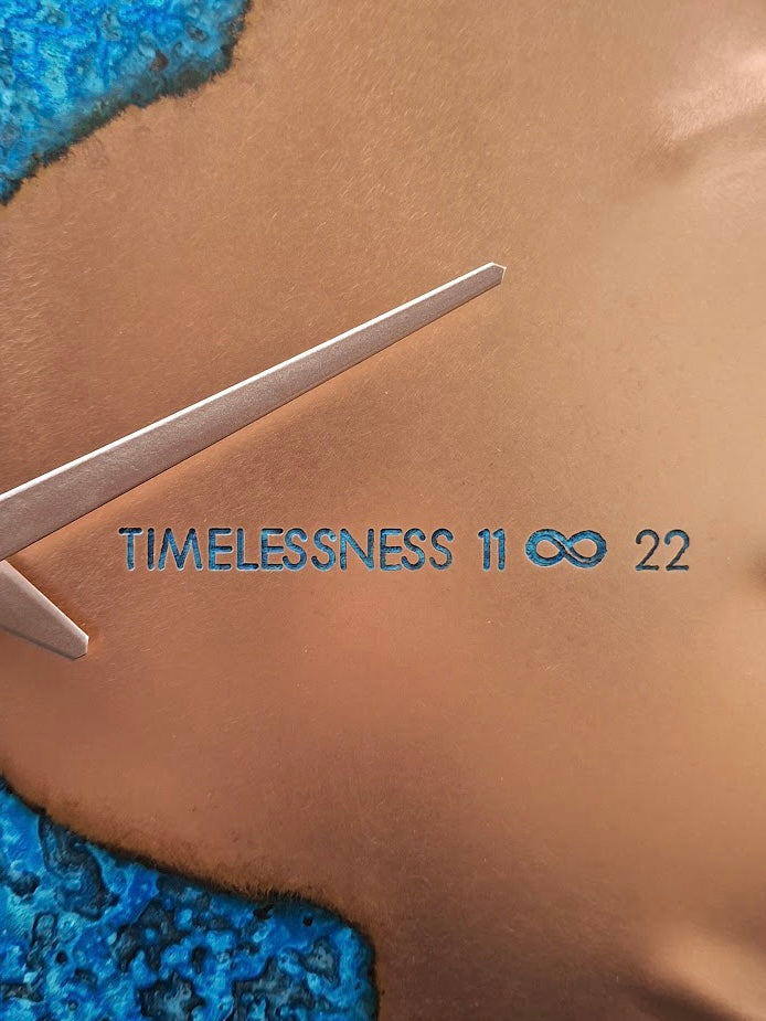 The text 'TIMELESSNESS 11 ∞ 22' on a Blue Patina Copper “Half Time” Clock, made by Empire Copper